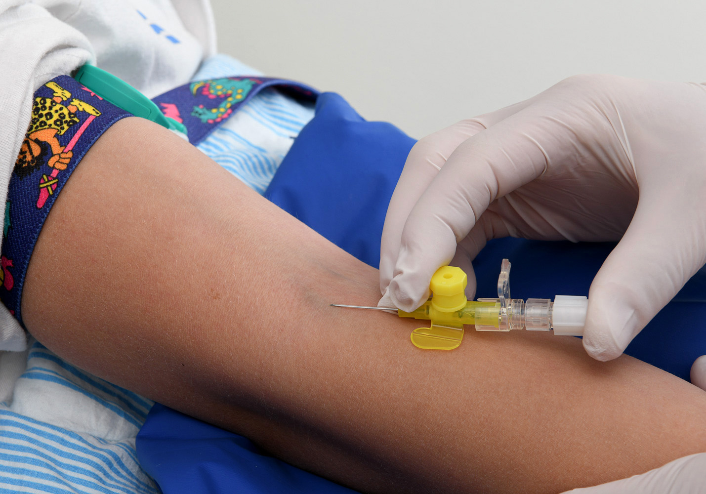 Lollo inserts the little tube in the crook of Mathilda’s arm using a needle.