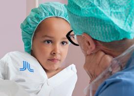 A girl in a green scrub cap looking deep into the eyes of a nurse.