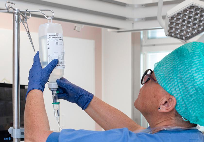 Nurse hanging a drip bag on a rack.