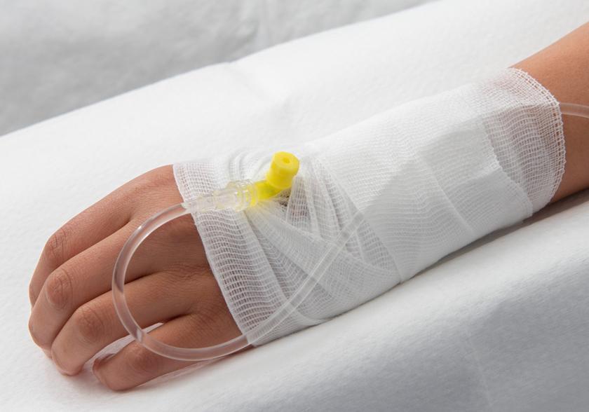Hand with plastic tube and drip. A wrap around the hand.